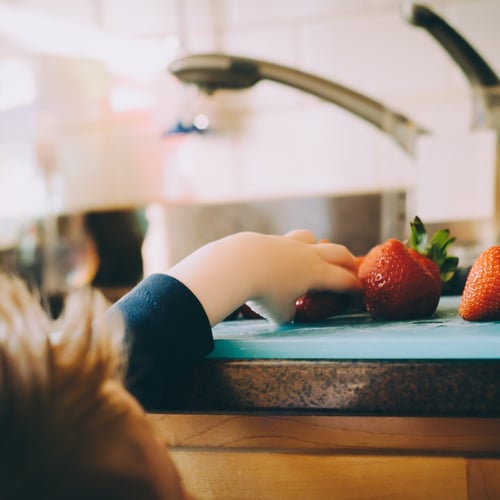 child grabbing strawberries off the counter